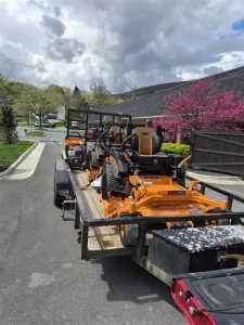 New commercial lawn mower and landscaping equipment secured on a trailer at West Point Cemetery for grounds maintenance operations.