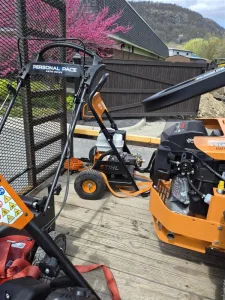 New landscaping equipment, including a mower and pressure washer, secured on a trailer at West Point Cemetery for grounds maintenance operations.