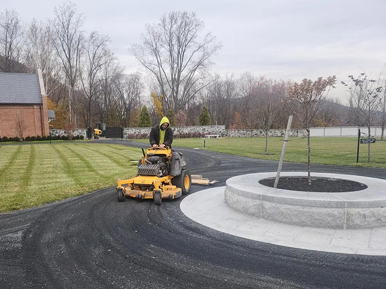 A groundskeeper with Supply Chain Management (SCM) smoothing a dirt pathway at West Point Cemetery