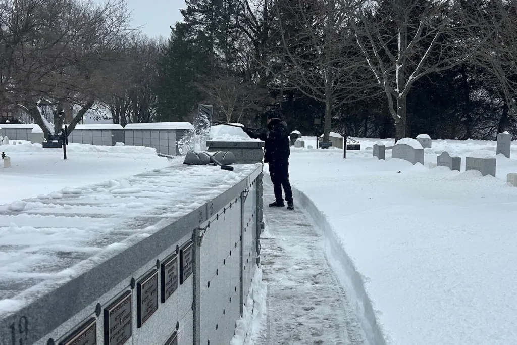 Member of the Supply Chain Management crew shoveling snow at West Point Cemetery